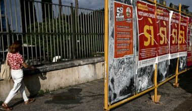 A woman walks past a series of campaign posters in downtown Rome promoting a Yes vote