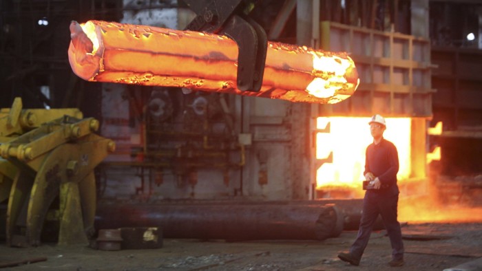 An employee walks behind a steel ingot at Sheffield Forgemasters in Sheffield