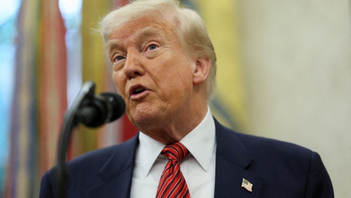 A close-up of Donald Trump speaking into a microphone in the Oval Office