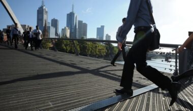 Morning commuters walk across Southgate Bridge in the central business district of Melbourne, Australia