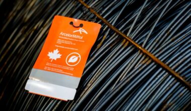 A close-up of a bundle of steel wire, with an orange ArcelorMittal tag attached. The tag indicates the steel is made in Canada from sustainable sources, featuring a maple leaf and leaf symbol