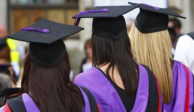 a rear view of three university graduates.