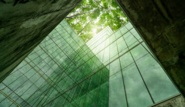 Eco-friendly building in modern city. Sustainable glass office structure with integrated greenery to reduce heat and carbon dioxide. Corporate architecture. Reducing CO2 emissions. Green environment.