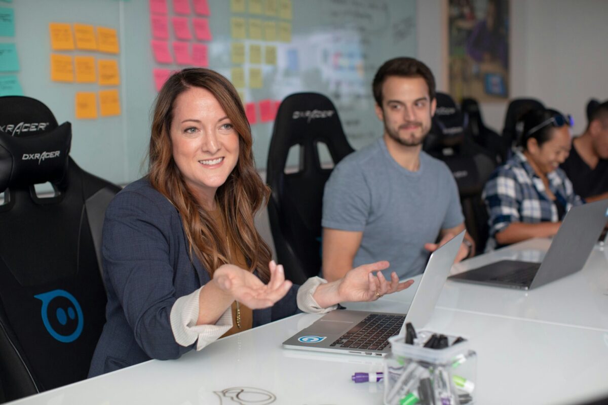 lady in blazer in front of computer and wall with sticky notes