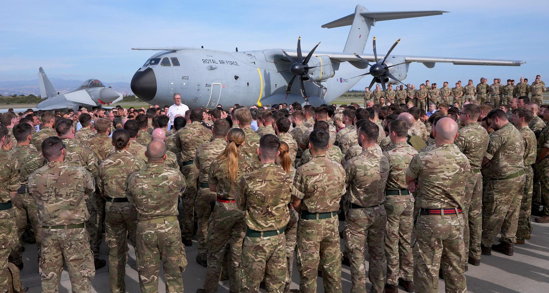 Der britische Premierminister Keir Starmer steht vor einer Maschine der Royal Air Force. Davor haben sich zahlreiche Soldaten versammelt.