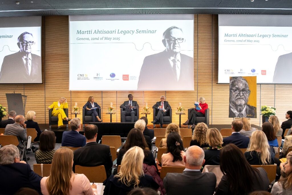 A panel of people on a stage with a crowd listening