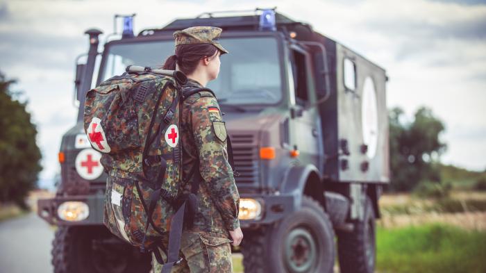 Bundeswehrsanitäterin vor einem Fahrzeug