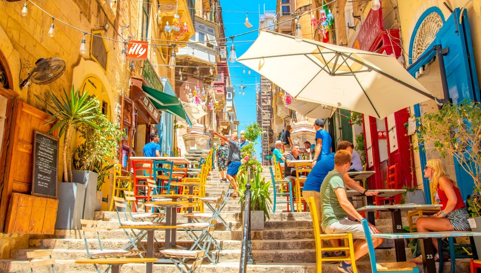 Outdoor cafe on a sunny Valletta street.