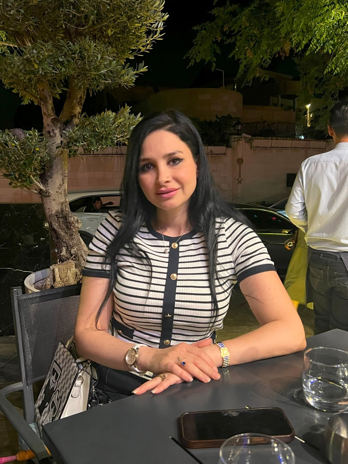 A person sits at a table on a patio.