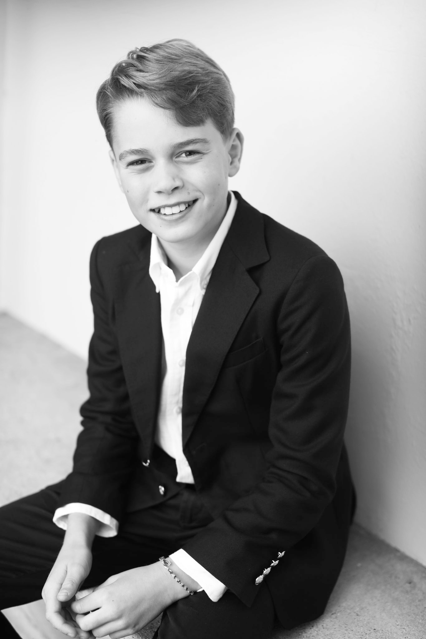 Black and white photo of Prince George smiling while wearing a suit.