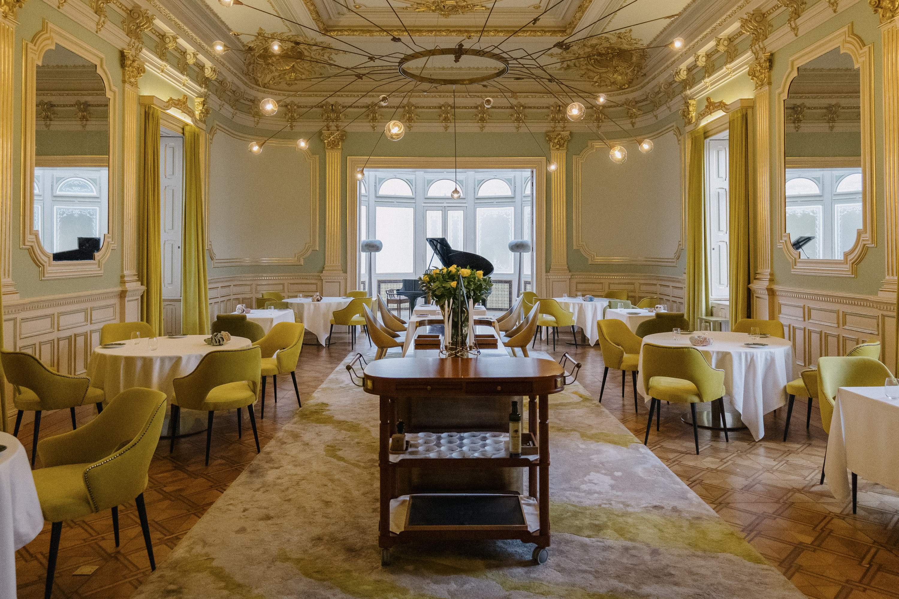 Elegant dining room with yellow chairs and a grand piano.