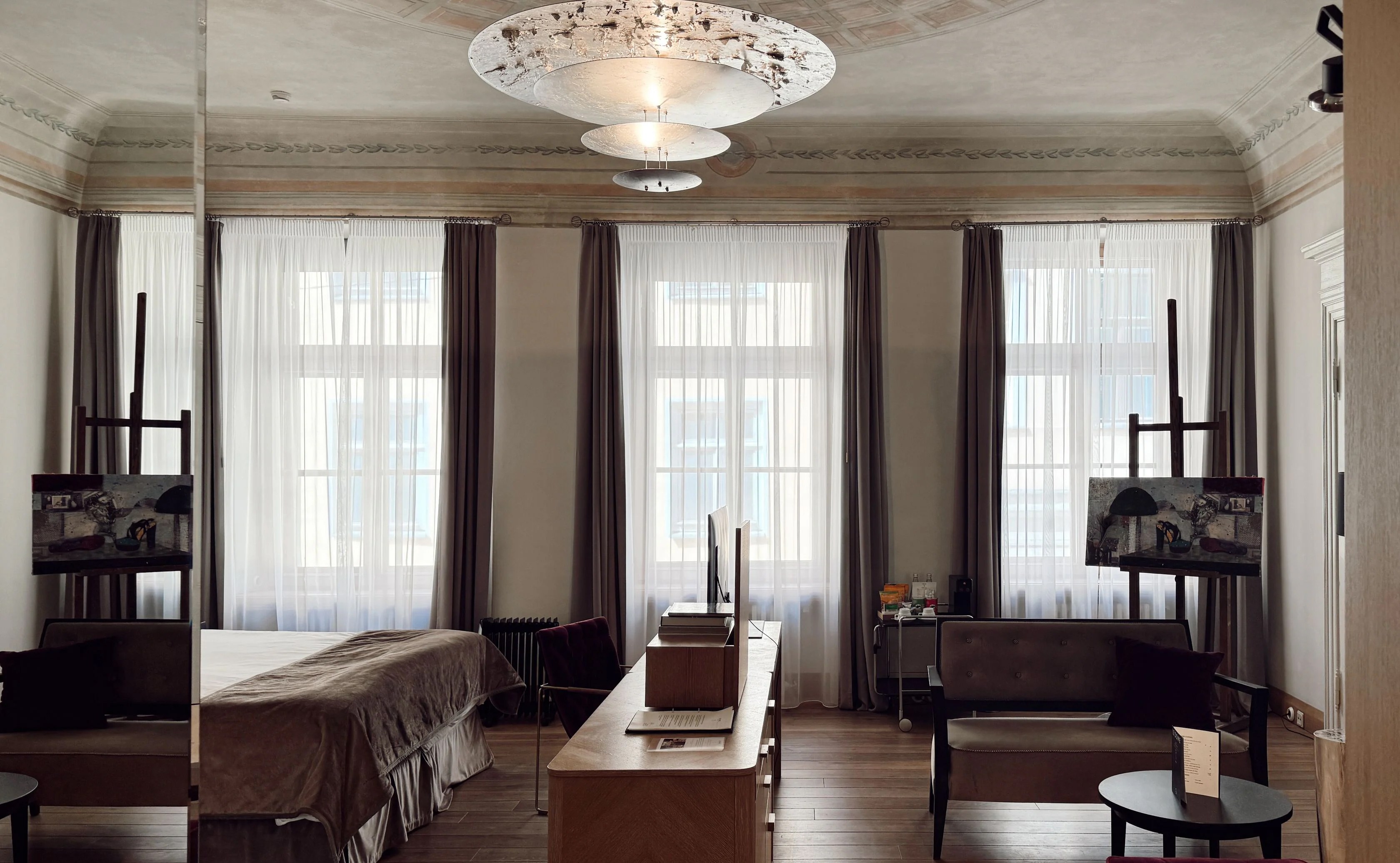 Hotel room with large windows, a bed, and artwork.