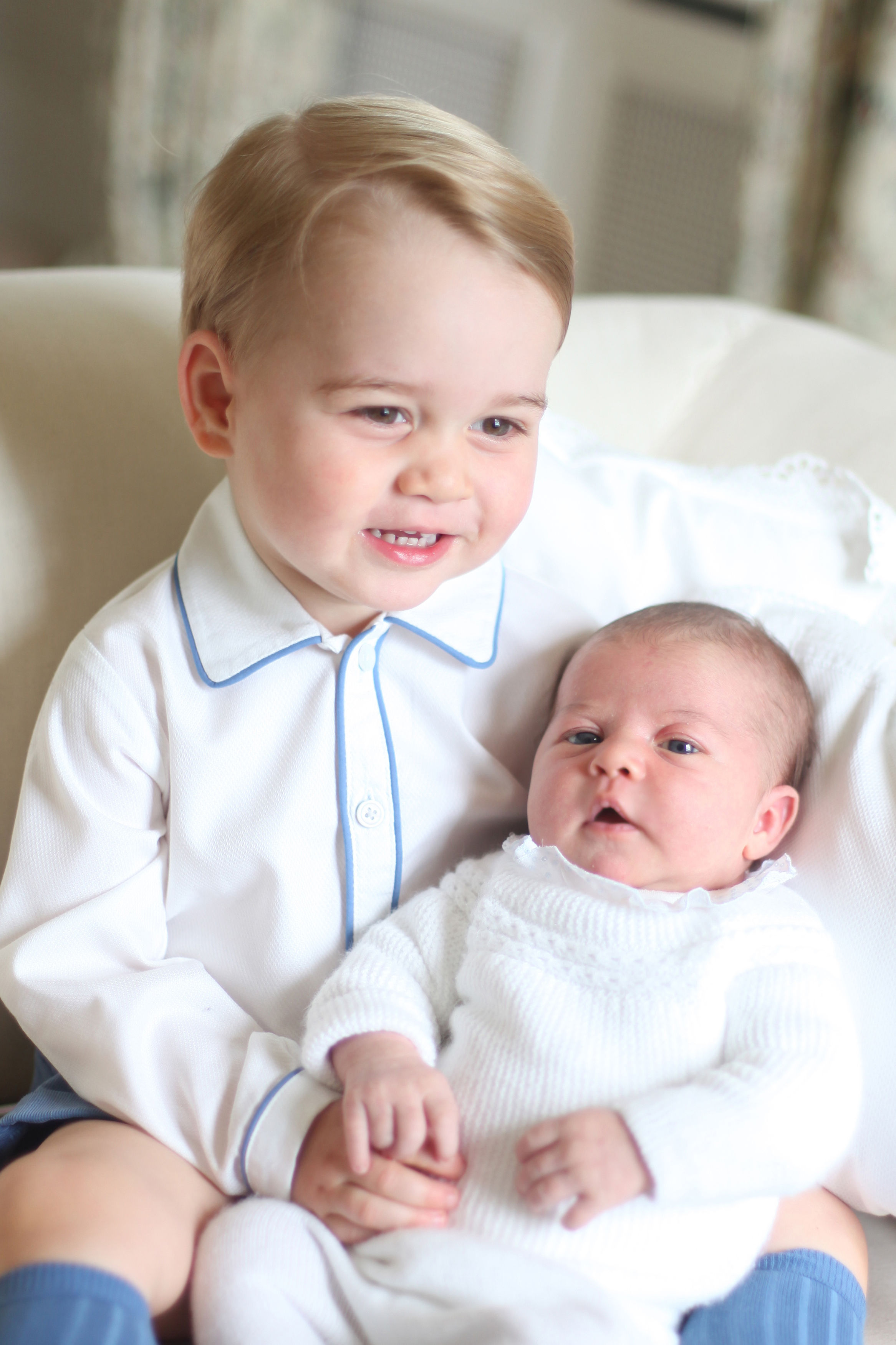 Prince George holding his baby sister, Princess Charlotte.