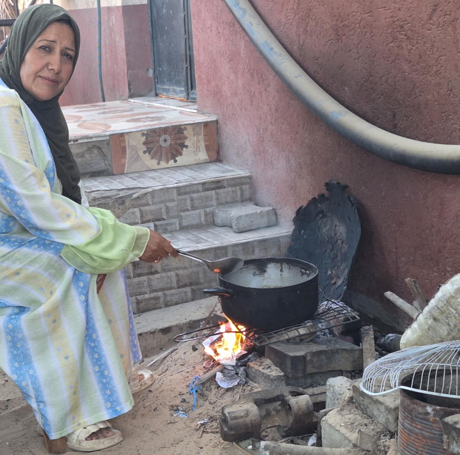 Woman cooking over an open fire.