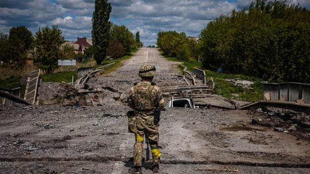 A soldier of the Kraken Ukrainian special forces unit observes the area at a destroyed bridge on the road near the village of Rus'ka Lozova, north of Kharkiv, on May 16, 2022. - Ukraine has said its troops have regained control of territory on the Russian border near the country's second-largest cit