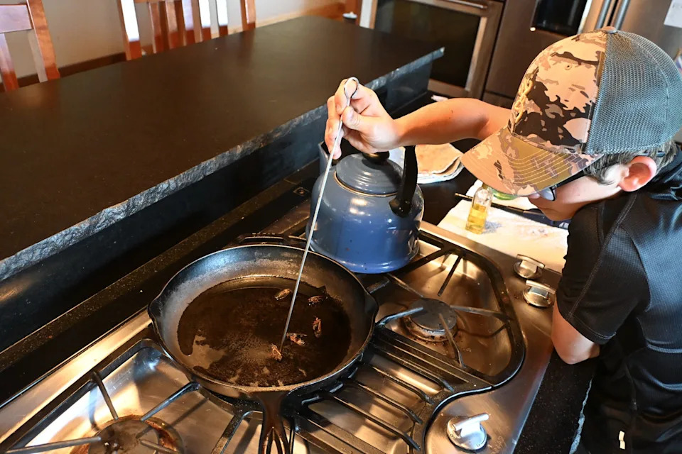 Silas Sorrell, 12, cooks cicadas in a cast iron skillet at his home in Harrison County, Kentucky, on June 1, 2025.