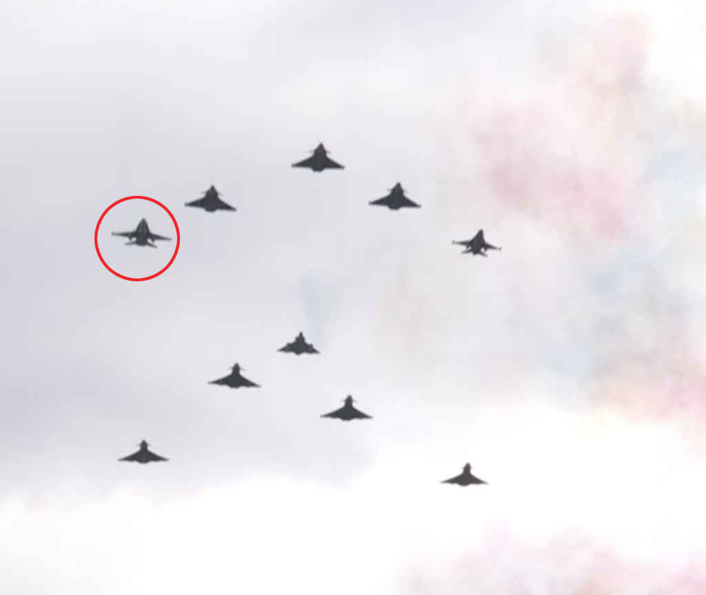 Formation de douze avions de chasse, volant en flèche dans un ciel nuageux.