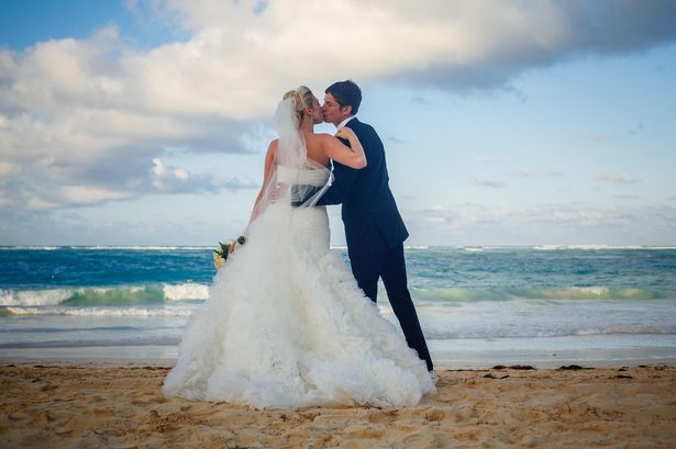 Bride and groom kissing on the beach, tropical destination wedding.