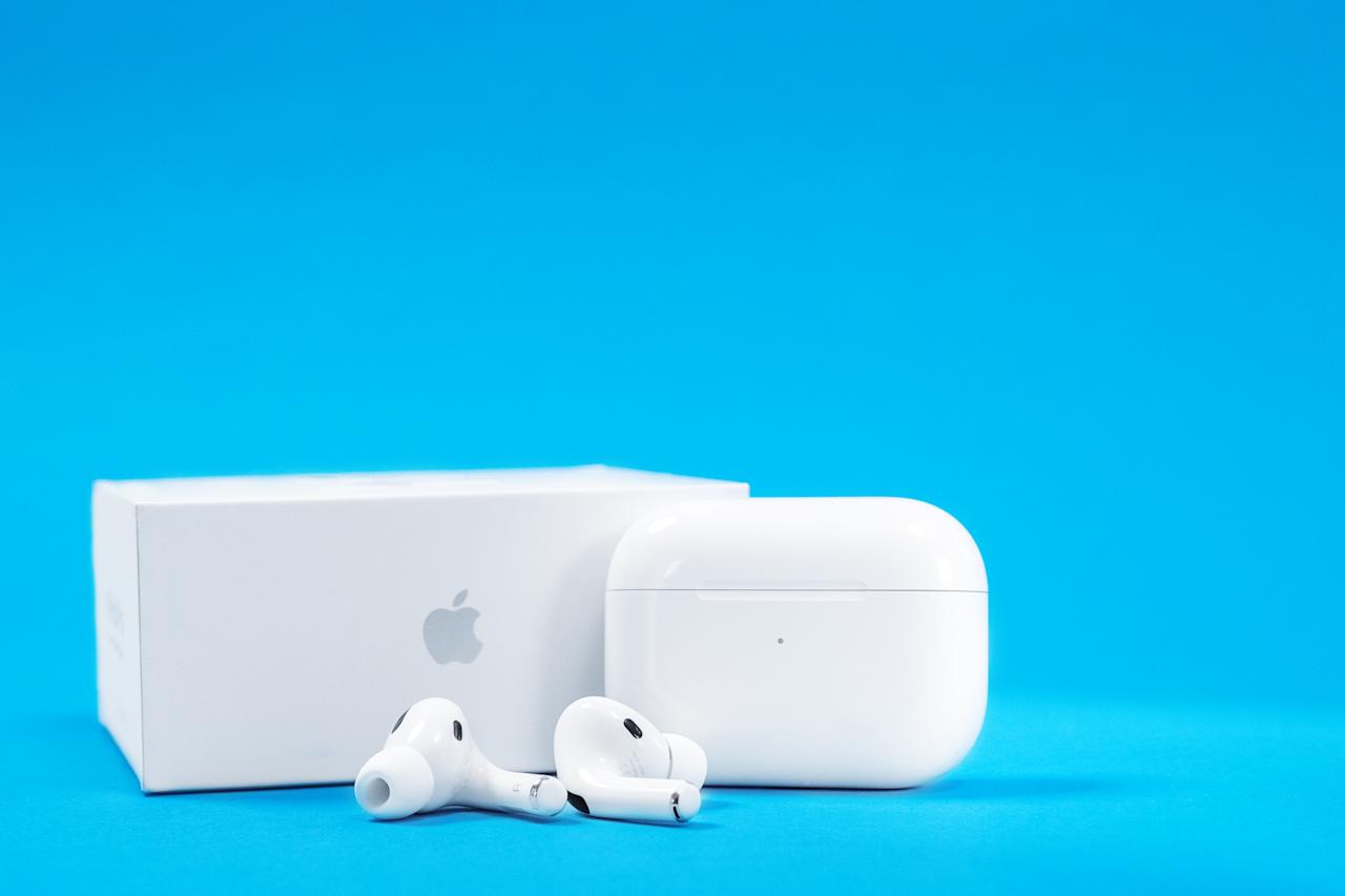 Rostov, Russia - July 06, 2020: New unpacked wireless headphones Apple AirPods Pro with opened rechargeable case and box on blue background, copy space for advertising text
