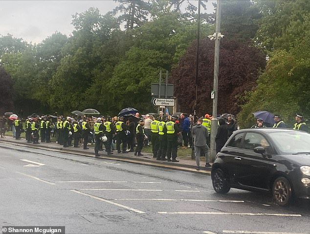 Police officers watch over the protesters in one of the designated protest zones
