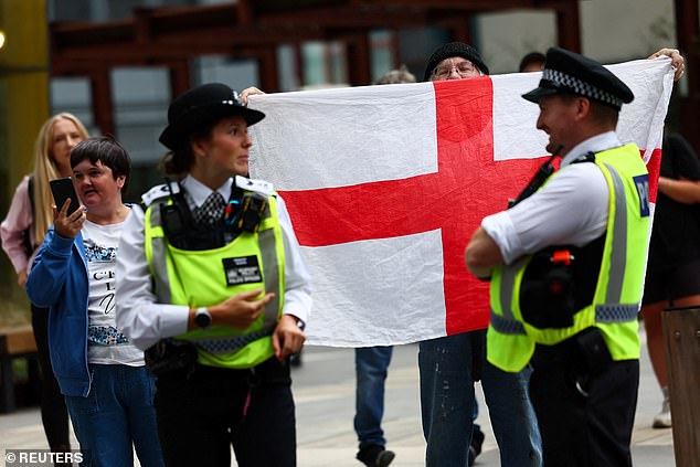 An anti-immigration demonstrator holds a flag of England, outside the Britannia International Hotel