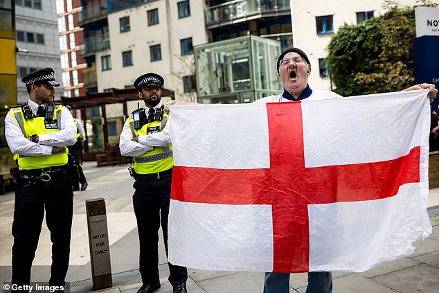 Asylum seekers could be made homeless if they refuse Home Office demands to move accommodation, the Government has warned (Pictured: A protestor outside a hotel in East London this week)
