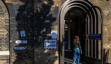 A woman entering a polling station through a large arched doorway in the UK.