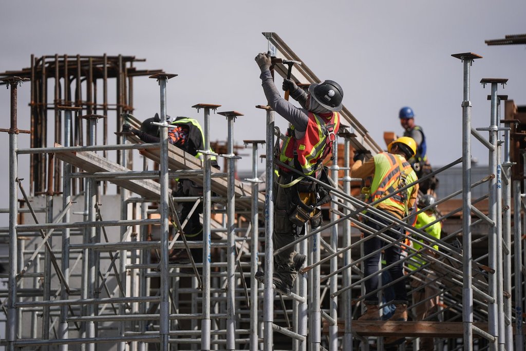 Construction workers work at the site of a condo tower under construction, in Delta, B.C., on Wednesday, July 2, 2025. Six months after U.S. President Donald Trump