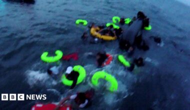 Yellow and red life-bands in the sea as people try and cling on to them. The picture is slightly blurry as it has been taken from a bodyworn camera.