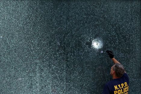 Poliisi tutki ampunajälkeä rakennuksen seinässä.
