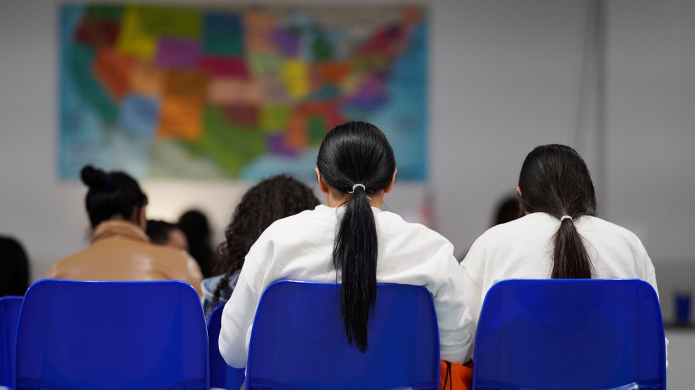 Three women sit in blue chairs, facing toward a map of the United States.