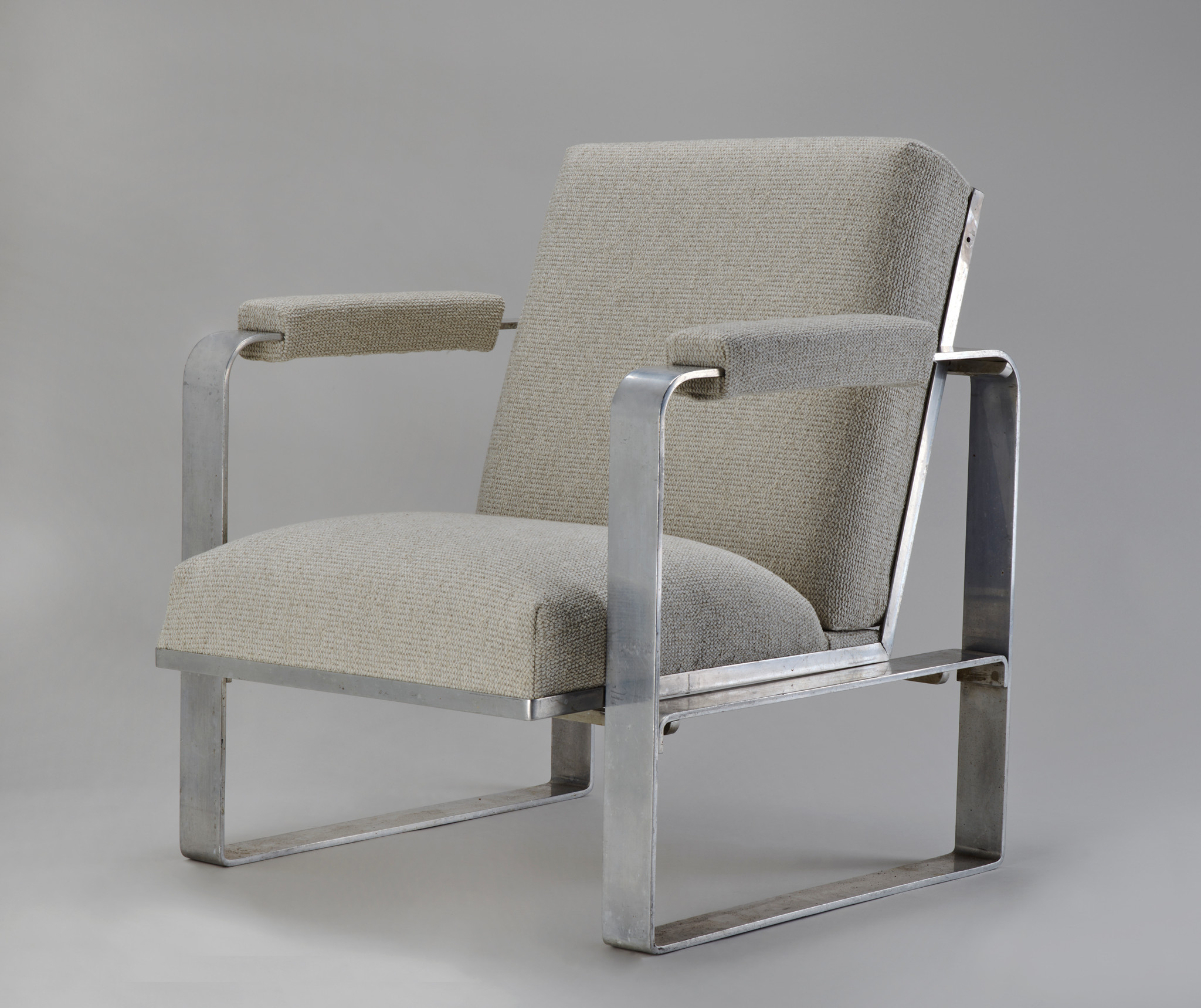 Fauteuil moderne avec cadre métallique argenté et coussins gris clair.