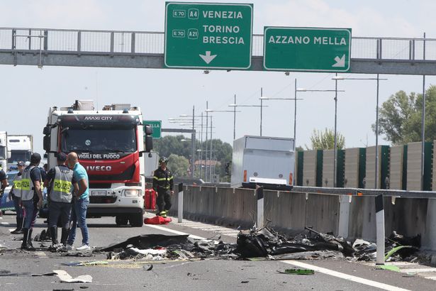 The scene on a highway in Italy. Emergency services officials can be seen next to the ruined debris of a plane