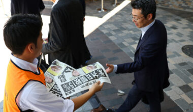 A staff from Yomiuri Shimbun newspaper distributes a special edition of the newspaper reporting the tariff deal agreement ...