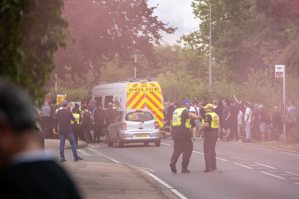 Police officers manage a protest near a hotel housing immigrants.