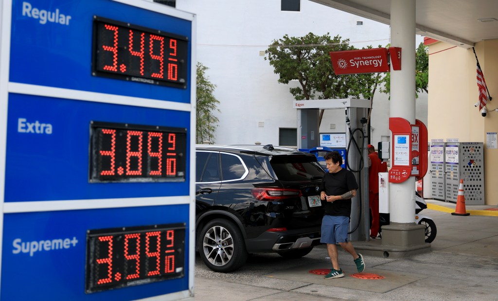 Person pumping gas at an Exxon station; gas prices displayed.