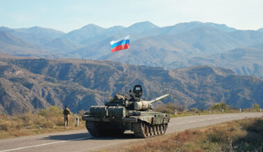 A service member of the Russian peacekeeping troops walks by a tank near the border with Armenia