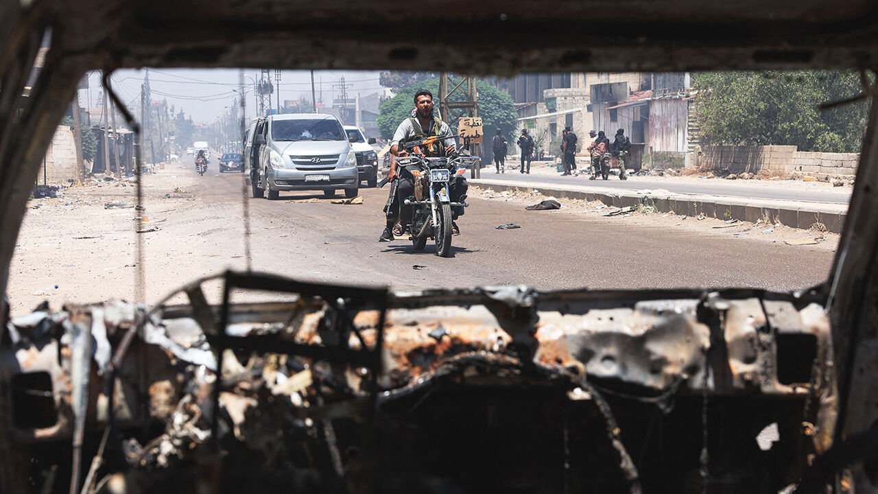 Bedouin fighters cross the al-Mazraa village in Syria's Suwayda governorate