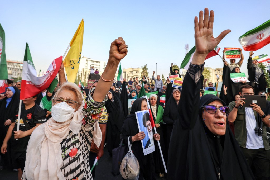 Iranians chant slogans and wave national flags as they celebrate a ceasefire between Iran and Israel at Enghlab Square in Tehran on June 24. A fragile ceasefire in the Iran-Israel war appeared to be holding on June 24, after 12 days of strikes that saw Israel and the United States pummel the Islamic republic's nuclear facilities.