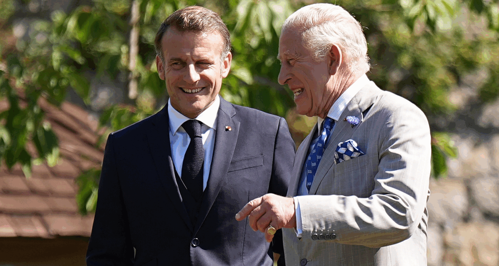 King Charles and Emmanuel Macron laughing in suits outside