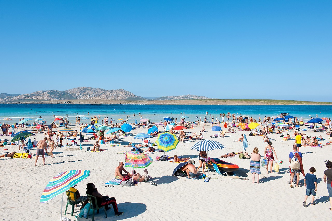 Menschen auf Liegestühlen auf dem La Pelosa Beach auf Sardinien