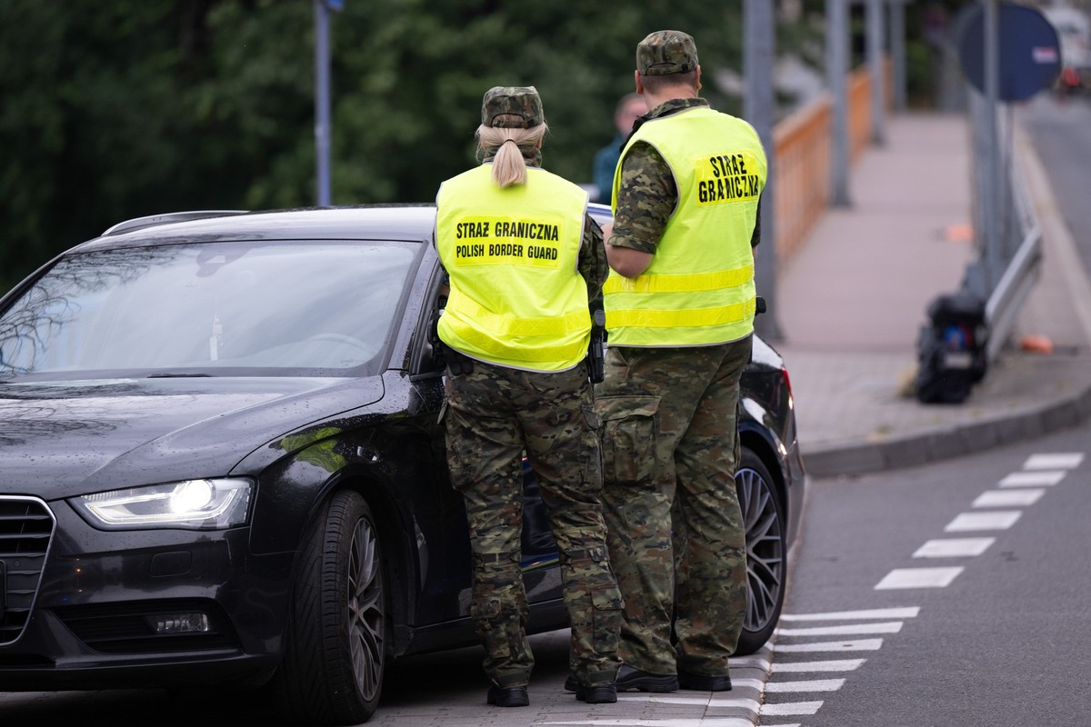 07.07.2025, Polen, Zgorzelec: Polnische Grenzschützer stehen auf der polnischen Seite hinter der Stadtbrücke von Görlitz und kontrollieren ein Fahrzeug. Polen hat vorübergehend die Grenzkontrollen an  ...