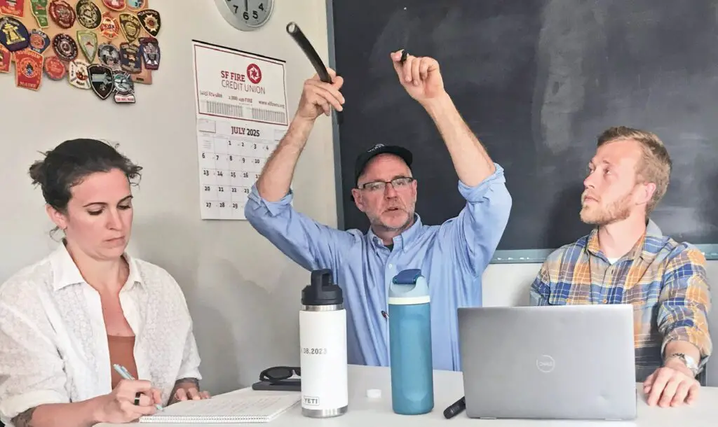 Dave Norman (center), Versant Power’s manager of regulatory support shows samples of two wires: on the right, copper wire used in power lines that is being replaced with a covered multi-wire aluminum wire. Also shown: Kate Klibansky of the Island Institute and Clayton Pokorny, researcher at National Renewable Energy Labs. BY TRESSA VERSTEEG