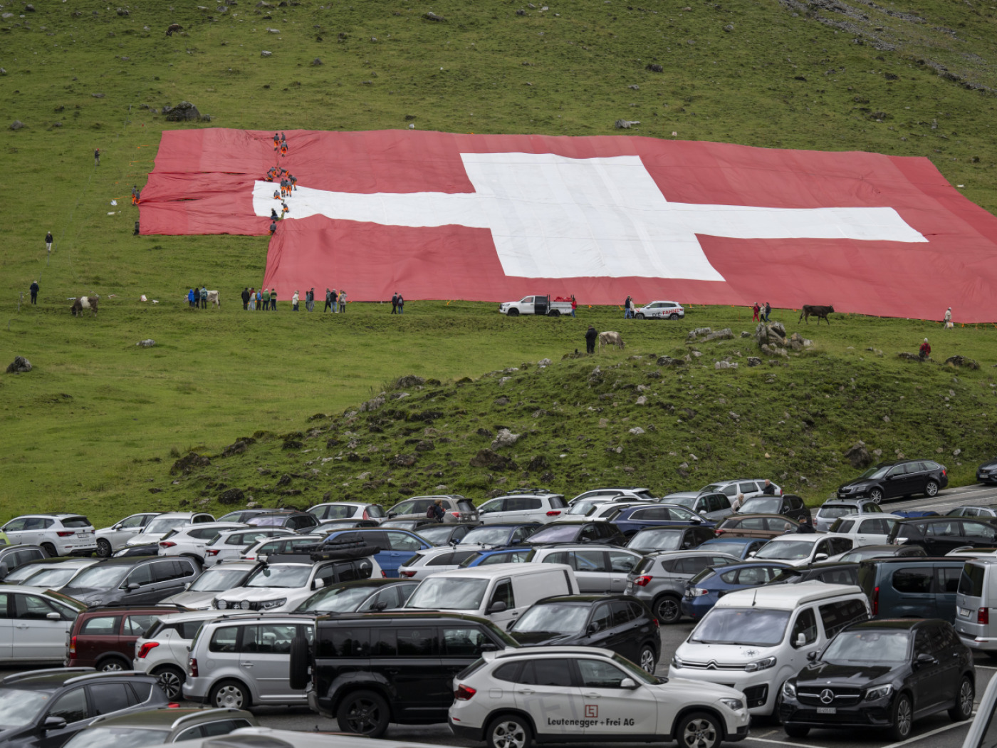 Giant Swiss flag torn by the wind at the foot of Säntis
