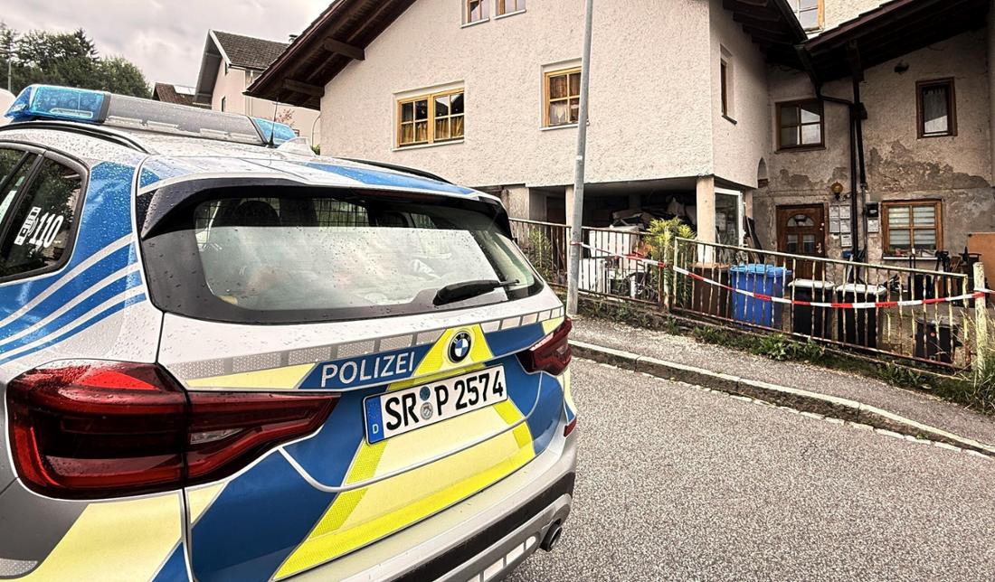 Ein Auto der Polizei steht vor einem Mehrfamilienhaus. In dem Haus im niederbayerischen Zwiesel sind drei Leichen gefunden worden.