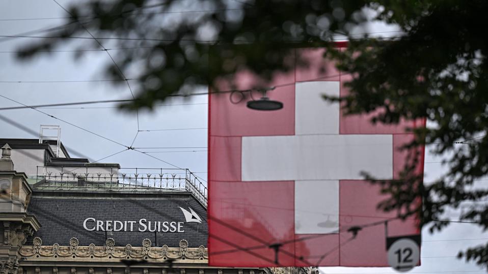 This photograph taken on August 31, 2023, shows a sign of Swiss bank Credit Suisse displayed on a building near a Swiss national flag in Zurich, after the announcement by UBS of the first results since Credit Suisse merger. Banking giant UBS has decided that the Swiss unit of its recently-swallowed rival Credit Suisse will be