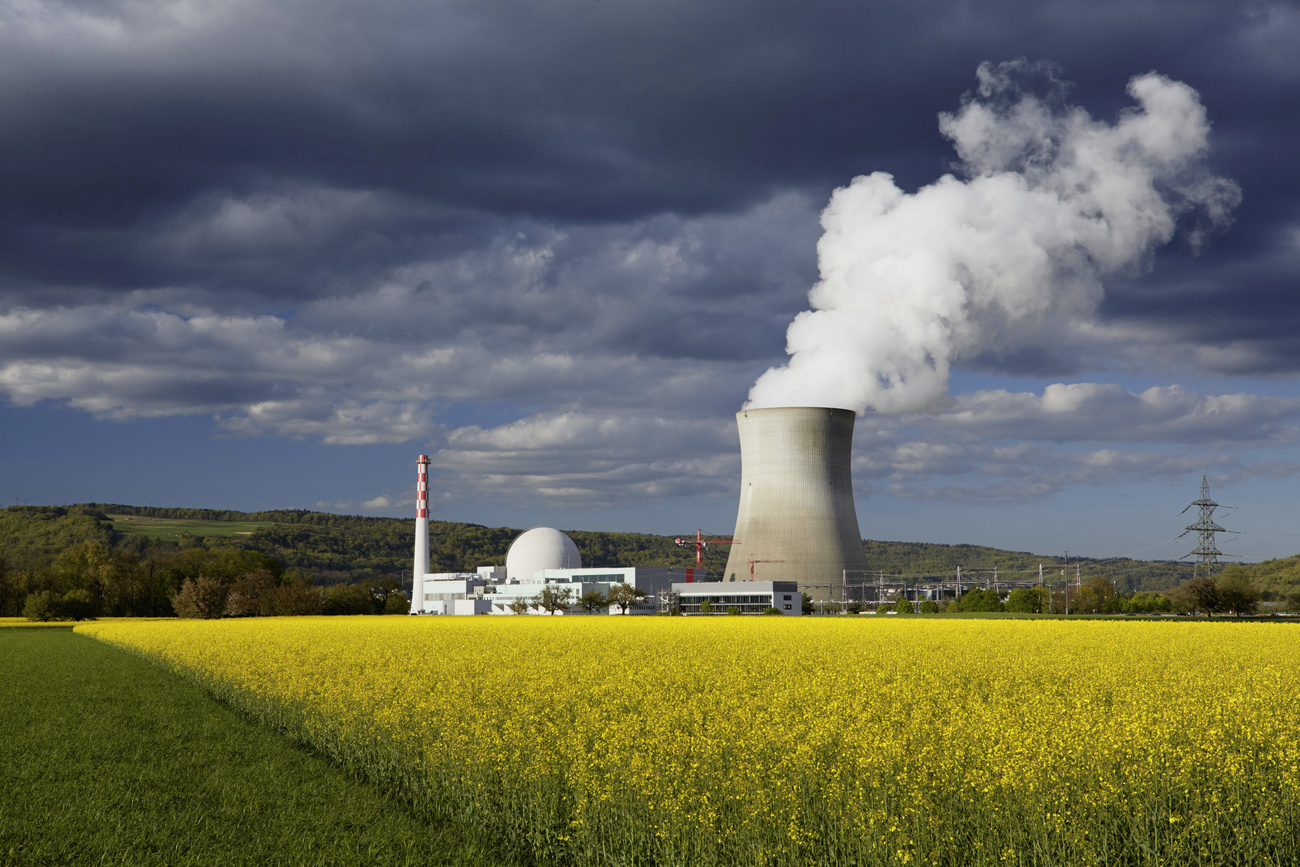 A nuclear power plant in Switzerland shown between dark clouds and bright rapeseed fields.