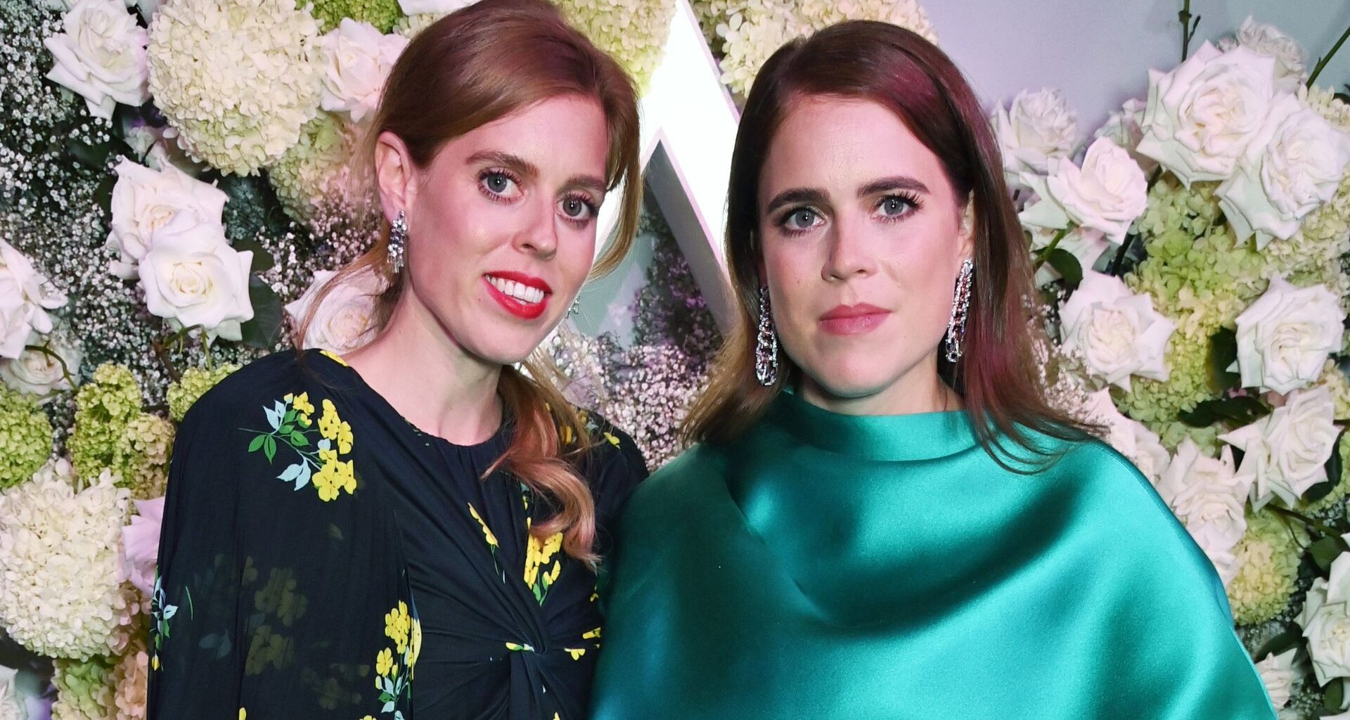 Princess Beatrice and Princess Eugenie pose smiling at the camera together