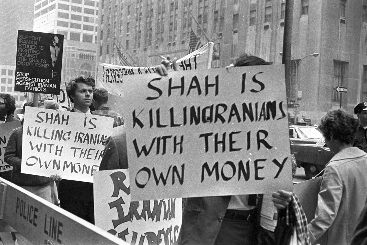Demonstrators protest Mohammad Reza Shah Pahlavi’s arrival in New York City. Signs read "Shah is killing Iranians with their own money."