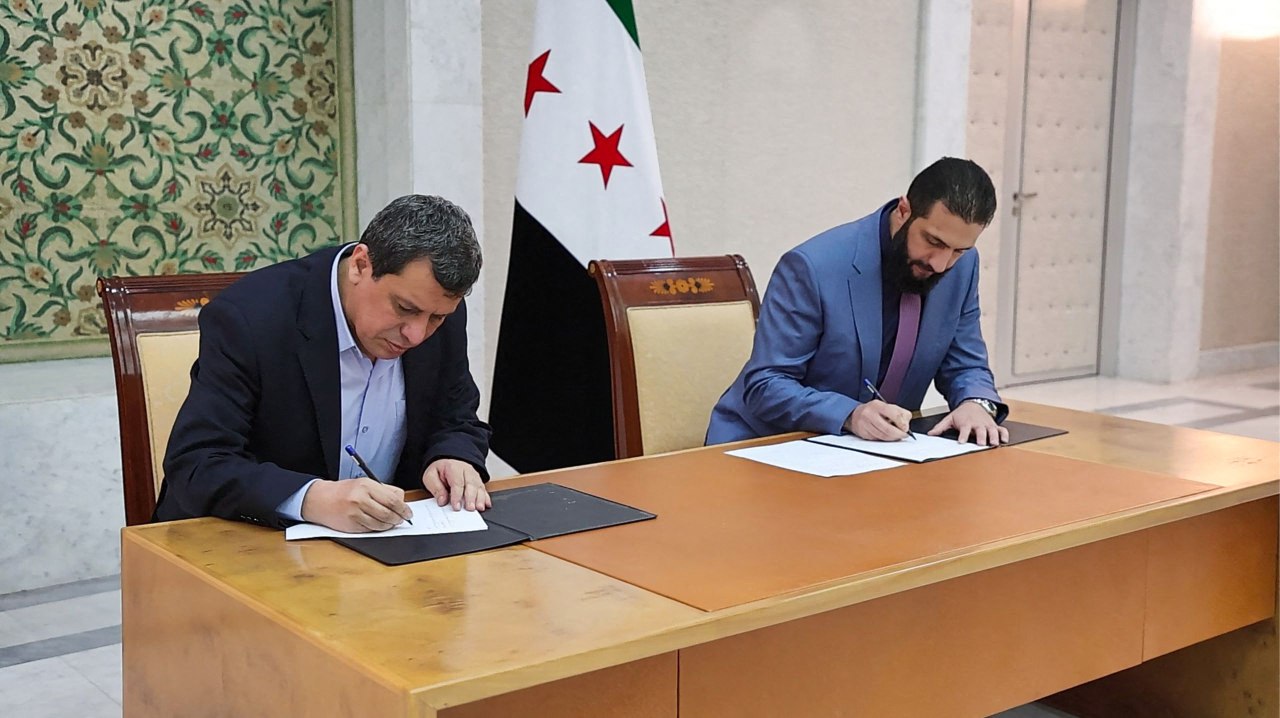 A handout picture released by the official Syrian Arab News Agency (SANA) shows Syria's interim president Ahmed al-Sharaa (R) and terrorist YPG-dominated SDF ringleader Mazloum Abdi signing an agreement, to integrate the institutions of the semi-autonomous Kurdish administration in the northeast into the national government, in the Syrian capital Damascus on March 10, 2025. (AFP Photo)